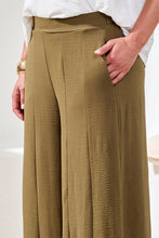 Load image into Gallery viewer, Model wearing olive green wide-leg pants with a white top and brown sandals on a neutral background.
