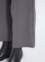 Load image into Gallery viewer, Close-up of the hems on grey pants and black boots against a white background.
