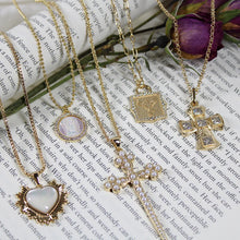Load image into Gallery viewer, Gold necklaces with various pendants on a book page with flowers.
