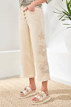 Load image into Gallery viewer, Person wearing beige pants with floral embroidery and sandals on a textured floor.
