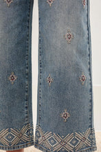 Load image into Gallery viewer, Blue jeans with decorative patterns and embellishments on a white background.
