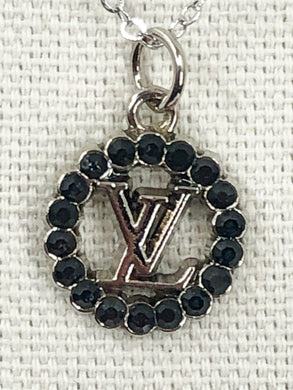 You'll adore the chic Babette Black Gem and Silver Vintage Louis Vuitton Zipper Pull Necklace. This dainty piece is ideal for wearing solo or layering with other favorite necklaces. With its perfect size and color scheme, this classic accessory will complement any ensemble.