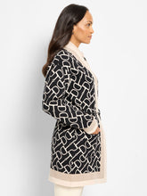 Load image into Gallery viewer, Woman wearing a black and white patterned long jacket against a white  background.
