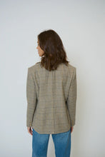 Load image into Gallery viewer, Woman wearing a plaid blazer over a cream shirt with blue jeans against a plain background.
