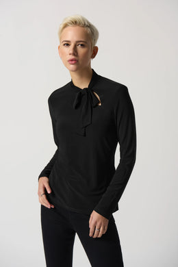 The Joseph Ribkoff long sleeve top features a slim silhouette, bow detail at the neckline, and an ultra-soft, stretchy fabric, allowing you to flaunt a feminine appearance. Ideal for wearing alone or for blending with a blazer, its design ensures a comfortable fit while elevating your look.  Color- Black. Bow design detail at the neck. Keyhole neckline. Fabric -96% Polyester, 4% Spandex.