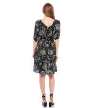 Load image into Gallery viewer, A charming scarf print puts a bohemian focus on this summer-ready dress. This statement-making dress features peasant sleeves, a tiered hem and flattering cinched waist and matching belt. Colors- Black and white. Short puff sleeve. Side pockets. Self-tie belt. Tiered hem. Cinched waist.
