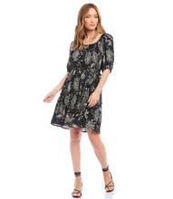 Load image into Gallery viewer, A charming scarf print puts a bohemian focus on this summer-ready dress. This statement-making dress features peasant sleeves, a tiered hem and flattering cinched waist and matching belt. Colors- Black and white. Short puff sleeve. Side pockets. Self-tie belt. Tiered hem. Cinched waist.
