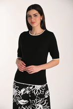 Load image into Gallery viewer, Woman wearing a black top and floral skirt on a white background.
