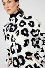 Load image into Gallery viewer, Woman wearing a white coat with black leopard print pattern and gold earrings against a white background.
