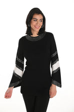 Load image into Gallery viewer, Woman wearing a long sweater with white and black patterned sleeves with crystal embellishments and black pants against a white background.
