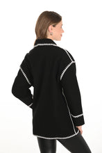 Load image into Gallery viewer, Woman wearing a black jacket with white trim and black leggings against a white background.
