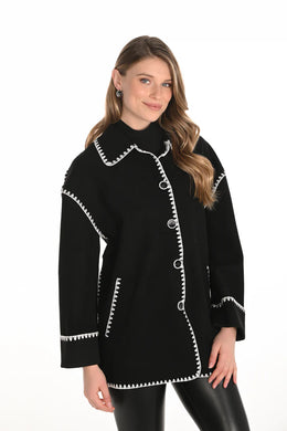 Woman wearing a black jacket with white trim and black leggings against a white background.