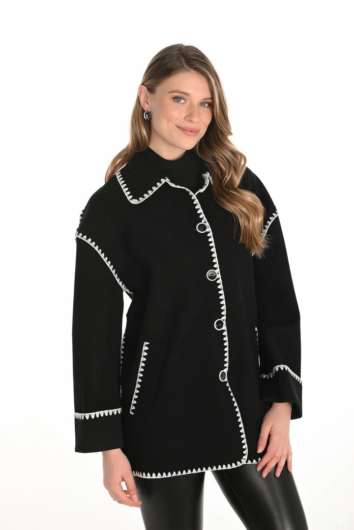 Woman wearing a black jacket with white trim and black leggings against a white background.