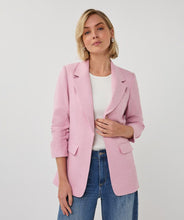Load image into Gallery viewer, Woman wearing a pink blazer over a white shirt and blue jeans on a white background.
