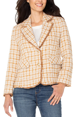 Woman wearing a gold plaid blazer and jeans against a white background.