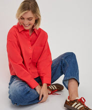 Load image into Gallery viewer, Woman wearing a red shirt, blue jeans and animal print tennis shoes sitting on the floor with a white background.
