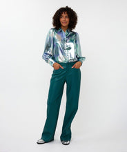 Load image into Gallery viewer, Model wearing a teal, blue and silver blouse with teal pants and silver shoes against a white background.
