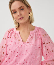 Load image into Gallery viewer, Close-up of woman wearing a pink eyelit blouse and gold floral statement earrings against a grey background.

