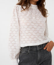 Load image into Gallery viewer, Woman wearing a white circle patterned turtle neck blouse and black jeans against a white background.
