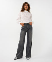 Load image into Gallery viewer, Woman wearing a white circle patterned turtle neck blouse, black jeans and silver shoes against a white background.
