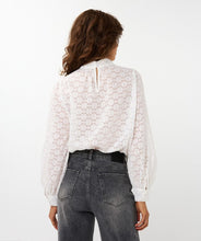 Load image into Gallery viewer, Woman wearing a white circle patterned turtle neck blouse and black jeans against a white background.
