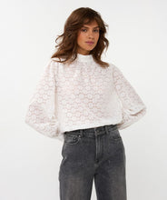 Load image into Gallery viewer, Woman wearing a white circle patterned turtle neck blouse and black jeans against a white background.
