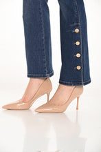 Load image into Gallery viewer, Close-up of blue jeans with button details and beige high-heeled shoes against a white background.
