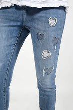 Load image into Gallery viewer, Add a touch of versatility and style to your wardrobe with the Blue Woven Denim Pant with Hearts, Pearls and Rhinestone Embellishments. This stunning piece features eye-catching heart embroidery, pearl and rhinestone details, and sparkling rhinestone hems, making it a statement piece for the spring/summer season. Don&#39;t miss out on the chance to sparkle and shine in these gorgeous jeans.
