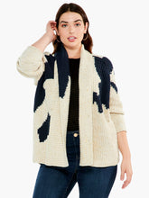Load image into Gallery viewer, A super comfy classic shaker knit with a few modern touches. The details start at the yarn, where the dominant oatmeal color is accented by flecks of yellow and charcoal to add even more texture and interest. The intarsia knit blocks of black and pink do the rest. A slightly chunkier weight plus the shawl collar and extra length means it&#39;s perfect as an outer layer on crisper days.  Color-Neutral Multi - oatmeal, (flecks of yellow and charcoal) black, pink. Intarsia knitting. Heavier weight.
