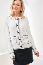 Load image into Gallery viewer, Woman wearing a white and navy contrast stitch cardigan over a navy pinstripe skort against a white background.
