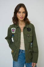 Load image into Gallery viewer, Woman wearing green shacket with patches, tank and blue jeans against a neutral background.
