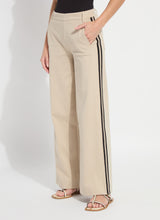 Load image into Gallery viewer, Model wearing khaki wide-leg pants with black stripes and strap sandals against a white background.
