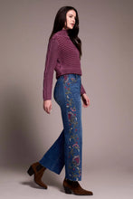 Load image into Gallery viewer, Woman wearing a purple sweater, blue jeans with floral embroidery and black boots against a neutral background.
