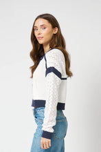 Load image into Gallery viewer, Woman wearing an ivory and navy cardigan with blue jeans on a light gray background.
