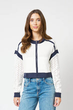 Load image into Gallery viewer, Woman wearing an ivory and navy zip up cardigan with blue jeans on a light gray background.
