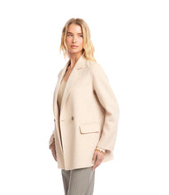 Load image into Gallery viewer, Woman wearing an oatmeal overcoat over an oatmeal v-neck top and striped pants against a white background.
