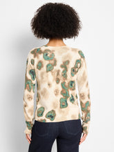Load image into Gallery viewer, Woman wearing a beige and metallic sweater with green camo pattern and blue jeans against a plain background.
