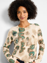 Load image into Gallery viewer, Woman wearing a beige and metallic sweater with green camo pattern against a plain background.
