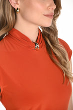 Load image into Gallery viewer, Close-up of a woman wearing an orange top with a mock neckline and gold jewel embellishment against a white background.
