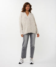 Load image into Gallery viewer, Woman wearing a light cardigan with pearls and feathers, grey pants and white sneakers against a white background.
