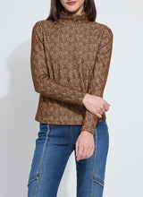 Load image into Gallery viewer, Woman wearing a brown textured long sleeve turtleneck and blue jeans with fringe trim against a white background.
