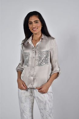 The Charise Champagne Blouse is made of a luxurious satin fabric that features chic sequin sparkle pockets. It also includes a button-down design with tab roll sleeves, as well as an elastic waistband with ties for an ideal fit.  Color- Champagne. Sequin pockets. Roll tab sleeves. Button down. Collared.