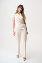 Load image into Gallery viewer, Woman wearing an off-white short sleeve draped blouse and off-white pants with off-white heels against a white background.
