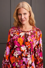 Load image into Gallery viewer, Steal the spotlight in this vibrantly printed blouse cut from flowy challis fabric with a hint of stretch. The popover v-neck, highlighted by delicate fabric ties, features a shirttail hem and long sleeves with elastic cuffs, completing the design. It seamlessly adds sophisticated style and vibrant color to your ensemble.
