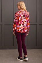 Load image into Gallery viewer, Steal the spotlight in this vibrantly printed blouse cut from flowy challis fabric with a hint of stretch. The popover v-neck, highlighted by delicate fabric ties, features a shirttail hem and long sleeves with elastic cuffs, completing the design. It seamlessly adds sophisticated style and vibrant color to your ensemble.
