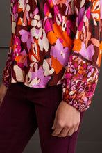 Load image into Gallery viewer, Steal the spotlight in this vibrantly printed blouse cut from flowy challis fabric with a hint of stretch. The popover v-neck, highlighted by delicate fabric ties, features a shirttail hem and long sleeves with elastic cuffs, completing the design. It seamlessly adds sophisticated style and vibrant color to your ensemble.
