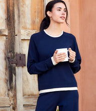 Load image into Gallery viewer, Woman holding a white mug and wearing a navy and cream sweater and matching pant against a wooden door.

