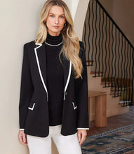 Load image into Gallery viewer, Woman wearing a black blazer with cream trim and cream pants in an indoor setting.
