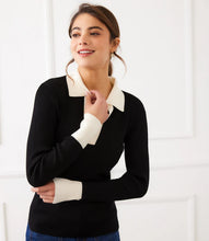 Load image into Gallery viewer, Woman wearing a black sweater with white collar and cuffs and jeans against a white background.
