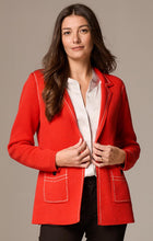 Load image into Gallery viewer, Woman wearing a red blazer over a white shirt and black pants against a beige background.
